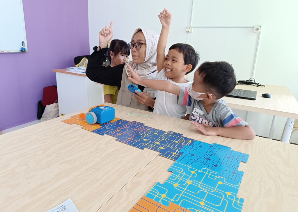 Guru dan beberapa murid sedang belajar coding menggunakan program LittleBot